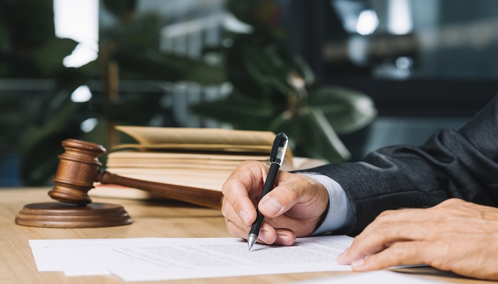 a man writing on paper next to a gavel